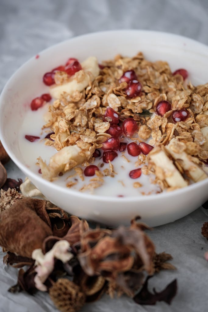 A nutritious oatmeal breakfast topped with banana, pomegranate seeds, and granola.