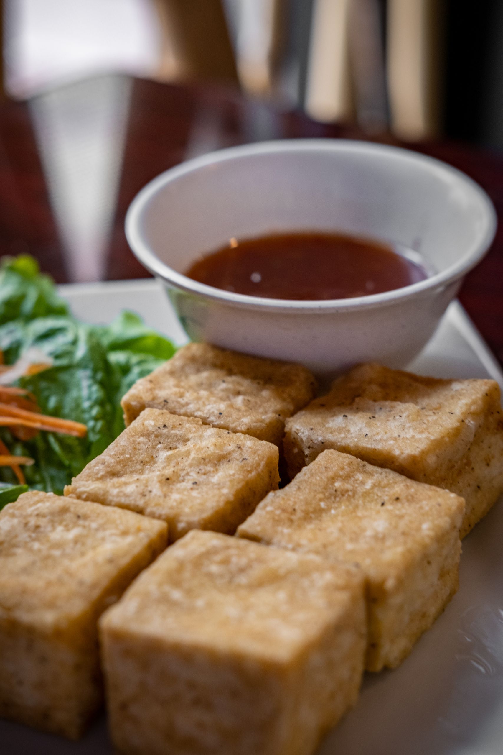 Delicious crispy tofu cubes served with dipping sauce and fresh greens for a healthy meal.