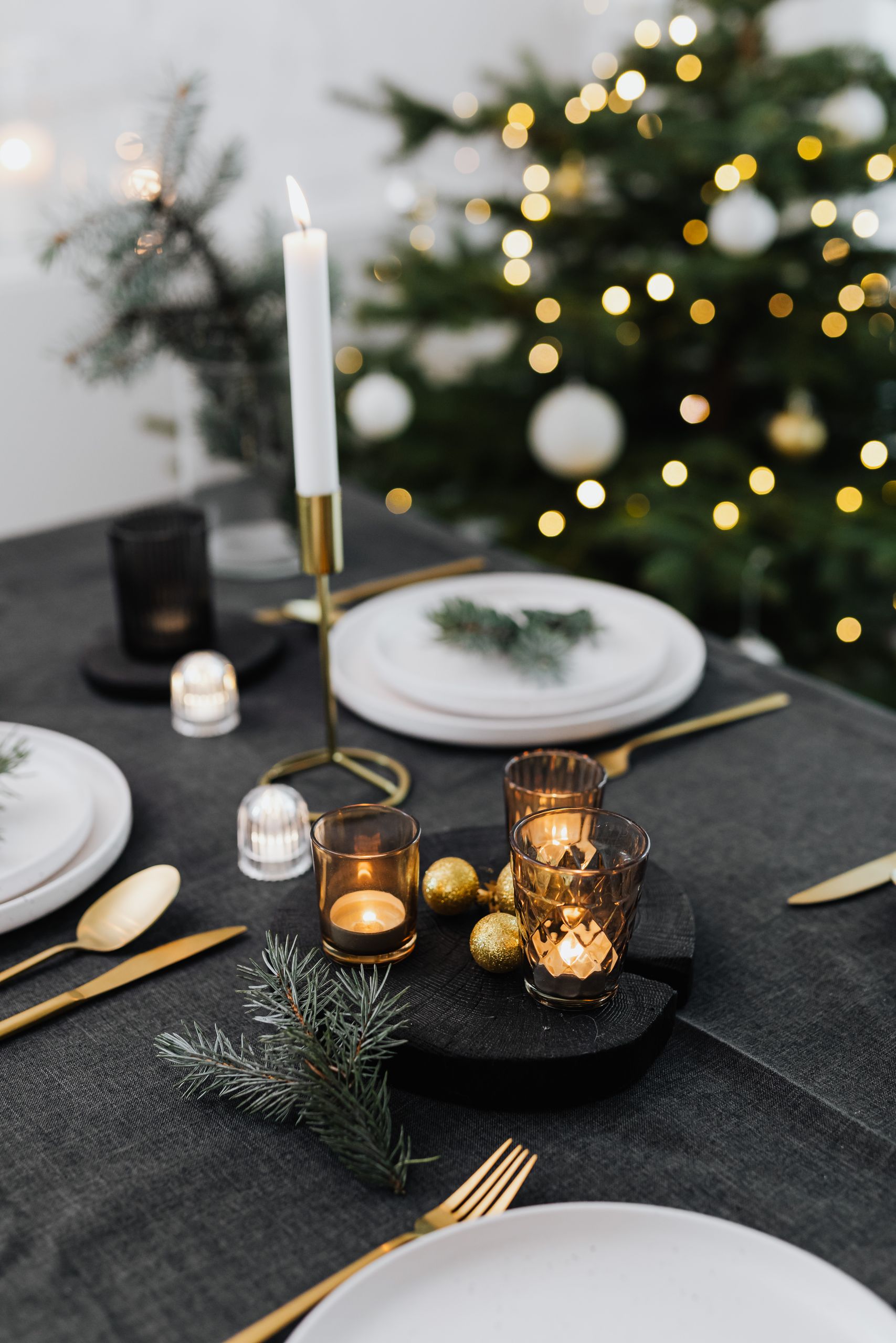 Festive dinner table with candles and Christmas tree for a cozy celebration.